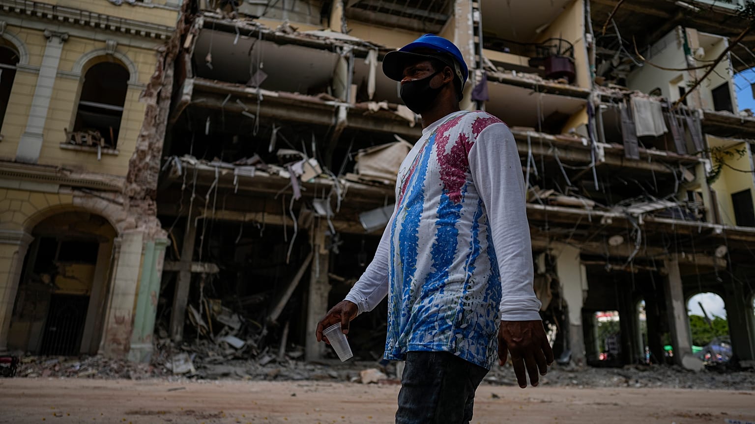 Un homme portant un tee-shirt avec le drapeau cubaine marche devant l'hôtel Saratoga, détruit à La Havane, le 7 mai 2022, Cuba
