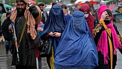 نساء أفغانيات يسرن في السوق القديمة بينما يقف مقاتل من طالبان في الحراسة، وسط مدينة كابول، أفغانستان، الثلاثاء 3 مايو 2022