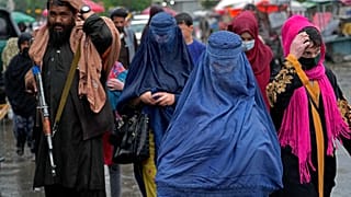 نساء أفغانيات يسرن في السوق القديمة بينما يقف مقاتل من طالبان في الحراسة، وسط مدينة كابول، أفغانستان، الثلاثاء 3 مايو 2022