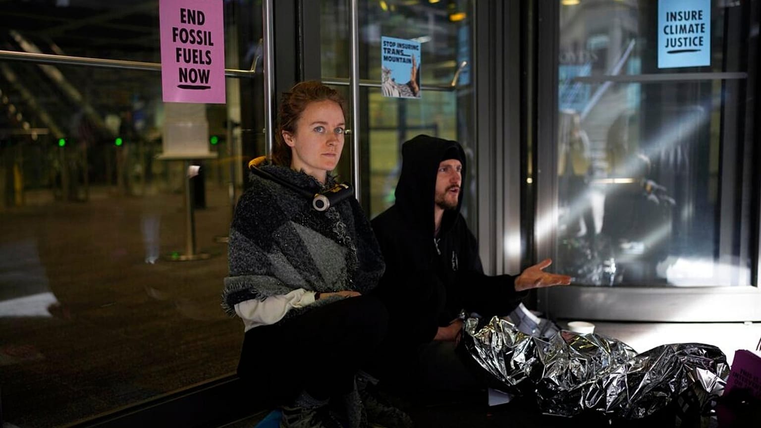 An Extinction Rebellion climate change protester sits with a lock around her neck attached to a bar on a door. 