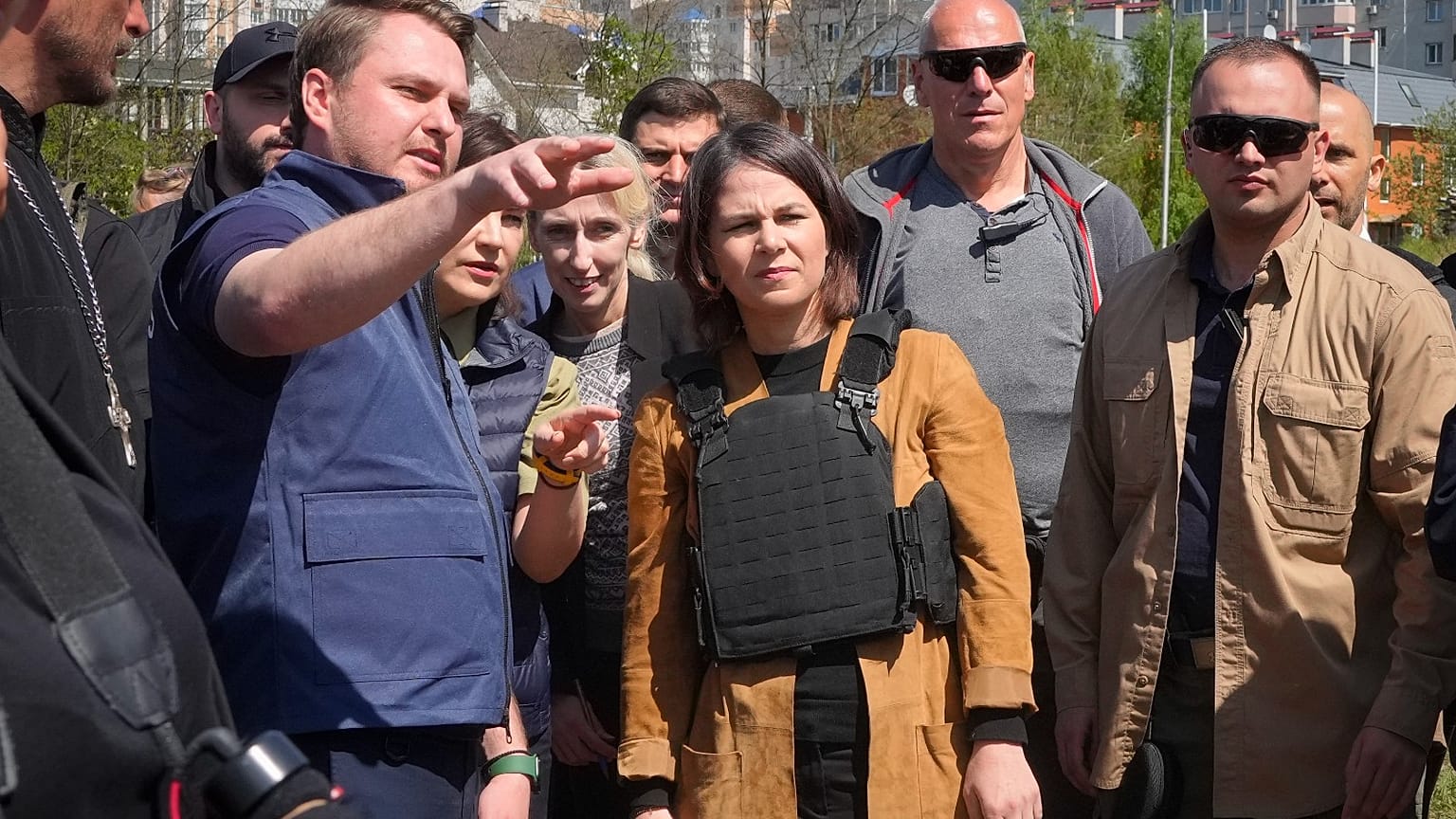German Foreign Minister Annalena Baerbock, center, and a Ukrainian War Prosecutor talk as they stand near a mass grave in Bucha, on the outskirts of Kyiv, 10 May 2022.