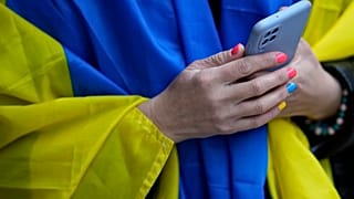 A woman wears a Ukrainian flag over her shoulders during a gathering outside Russia's embassy in Lisbon.