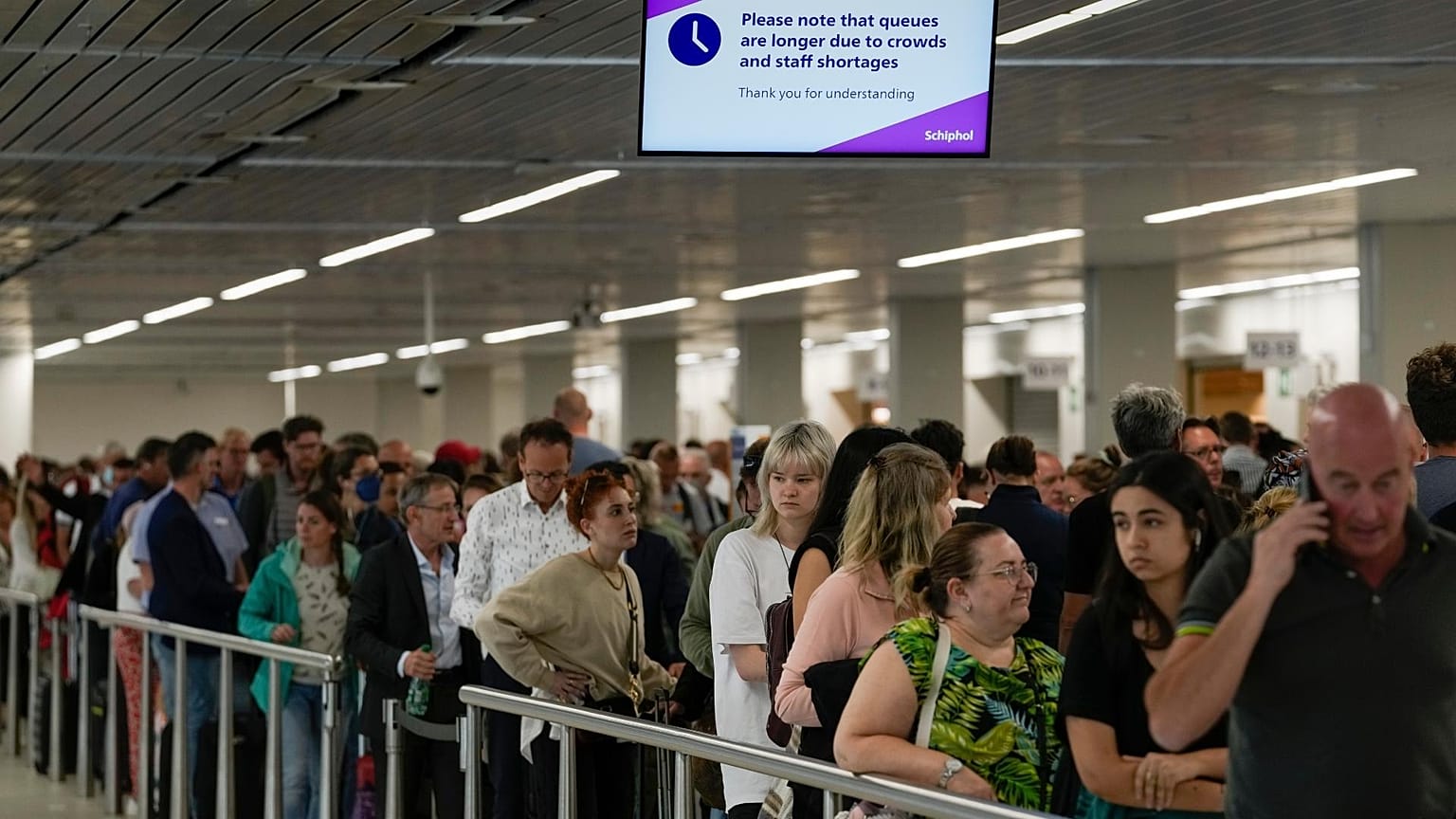 Travellers wait in long lines to check in and board flights at Amsterdam's Schiphol Airport.