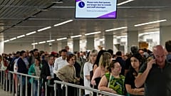 Travellers wait in long lines to check in and board flights at Amsterdam's Schiphol Airport.