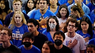 Estudiantes universitarios escuchan el himno nacional durante un partido de voleibol en Los Ángeles, EEUU
