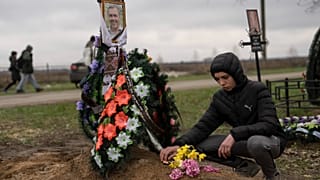 Yura Nechyporenko, 15, places a chocolate at the grave of his father Ruslan Nechyporenko at the cemetery in Bucha, on the outskirts of Kyiv, Ukraine, on April 21, 2022.