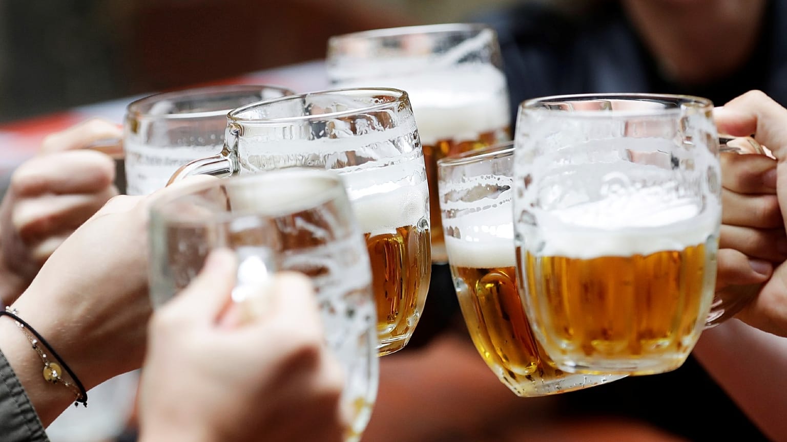 People enjoy beers at an outdoor seating section of a pub in Prague