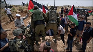 القوات الإسرائيلية تمنع نشطاء سلام فلسطينيين وإسرائيليين من تحريك حجر يسد طريقًا يمر بالقرب من مستوطنة مزبي يائير اليهودية الإسرائيلية، مسافر يطا، 13/05/2022 الضفة الغربية