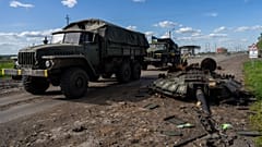 Ukrainian army vehicles drive past the remains of a Russian tank in north Kharkiv, east Ukraine, Friday, May 13, 2022.