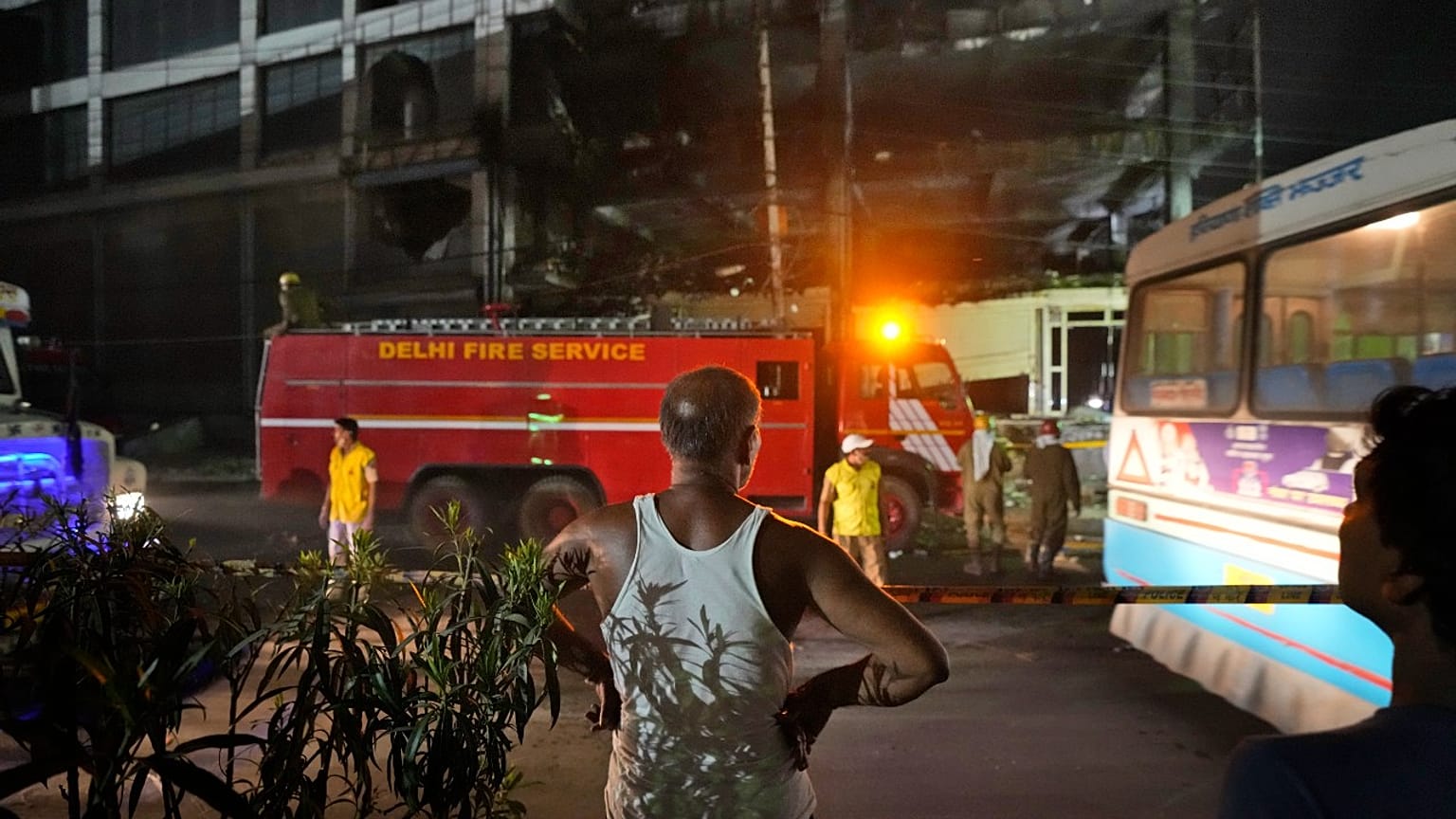 A person watches as fire officials douse a fire in a four storied building, in New Delhi, India, Saturday, May 14, 2022.