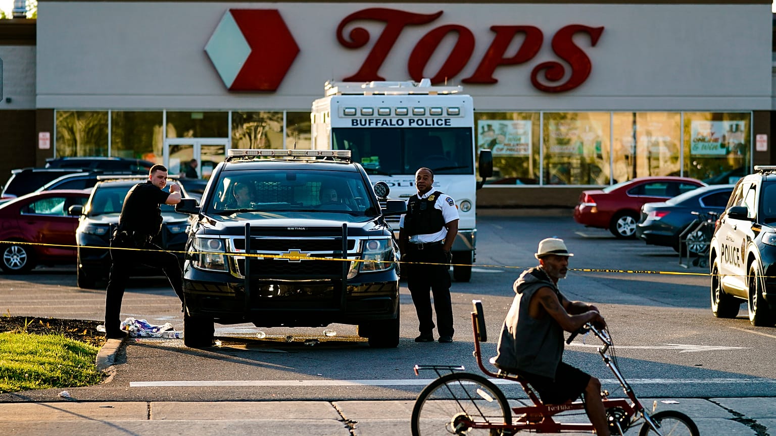 Un ciclista se detiene al pasar por la escena de un tiroteo en un supermercado, en Buffalo, Nueva York, el domingo 15 de mayo de 2022. 