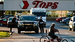 Un ciclista se detiene al pasar por la escena de un tiroteo en un supermercado, en Buffalo, Nueva York, el domingo 15 de mayo de 2022. 