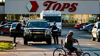 Un ciclista se detiene al pasar por la escena de un tiroteo en un supermercado, en Buffalo, Nueva York, el domingo 15 de mayo de 2022. 