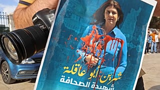 صحفي يرفع ملصقا لشرين أبو عاقلة تنديدا لاغتيالها في مسيرة في مدينة بيت لحم، الضفة الغربية. 