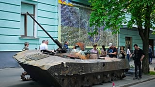 People look at a Russian military vehicle destroyed by the Ukrainian troops and taken to the capital Kyiv as a reminder of war, May 12, 2022.