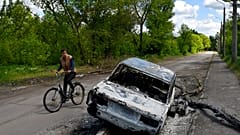 Radfahrer und zerstörtes Auto im Osten der Ukraine