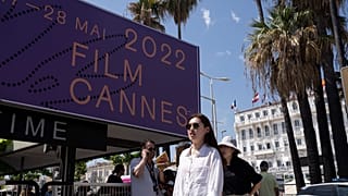 A filmfesztivál molinója előtt sétáló nő Cannes-ban.