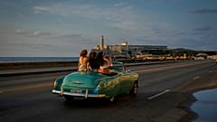 Turistas passeiam num carro antigo no Malecón, em Havana