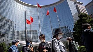 People wearing face masks stand in line for coronavirus tests at an office building in the Dongcheng district of Beijing, Tuesday, April 26, 2022.