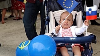 A baby girl waves the European flag along with the Slovenian one while attending a celebration in Brussels, July 11, 2006.
