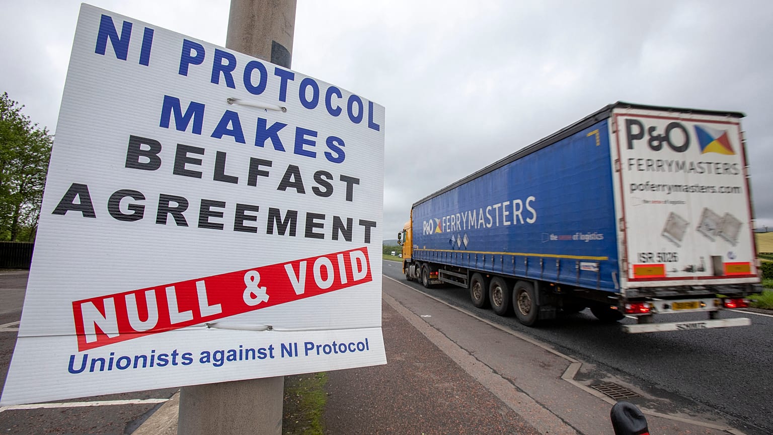 A lorry passes an anti 'Northern Ireland Protocol' sign as it is driven away from Larne port, north of Belfast in Northern Ireland, after arriving on a ferry, on May 17, 2022.
