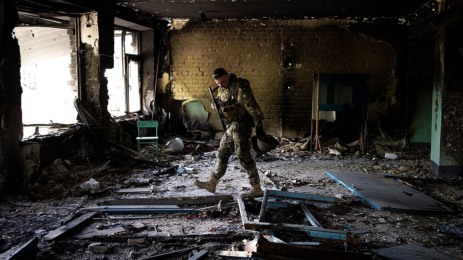 A Ukrainian serviceman inspects a school damaged during a battle between Russian and Ukrainian forces in the village of Vilkhivka near Kharkiv on 20 May 2022