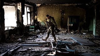 A Ukrainian serviceman inspects a school damaged during a battle between Russian and Ukrainian forces in the village of Vilkhivka near Kharkiv on 20 May 2022
