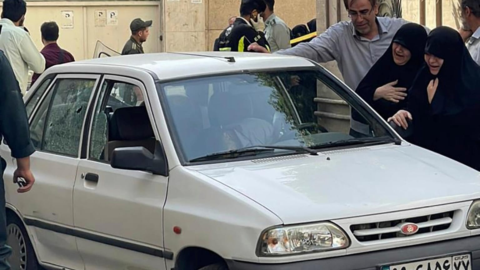 family members of Col. Hassan Sayyad Khodaei weep over his body at his car after being shot by two assailants in Tehran, Iran, Sunday, May 22, 2022.