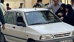 family members of Col. Hassan Sayyad Khodaei weep over his body at his car after being shot by two assailants in Tehran, Iran, Sunday, May 22, 2022.