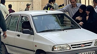 family members of Col. Hassan Sayyad Khodaei weep over his body at his car after being shot by two assailants in Tehran, Iran, Sunday, May 22, 2022.