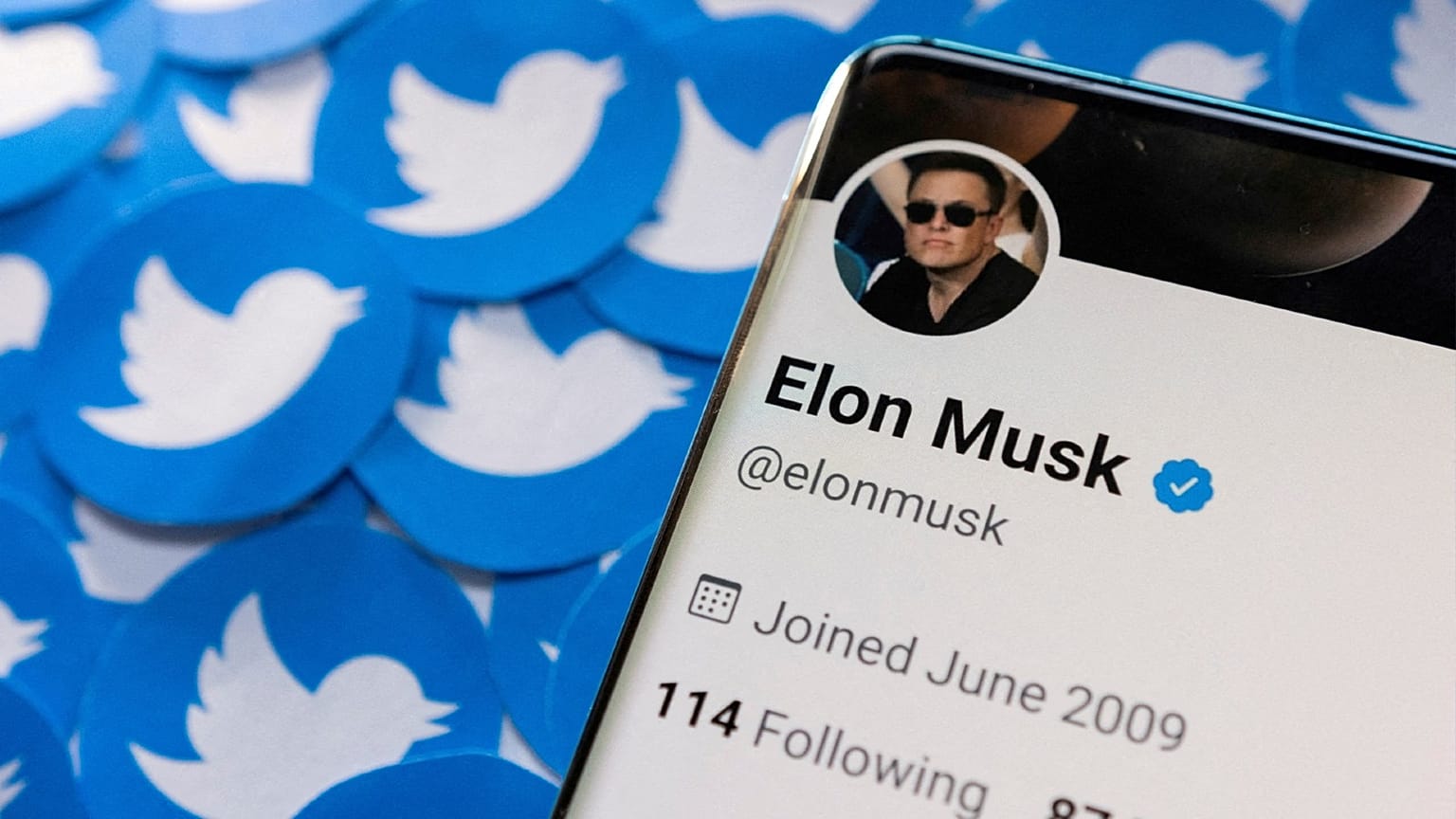 FILE PHOTO: Elon Musk's Twitter profile is seen on a smartphone placed on printed Twitter logos in this picture illustration taken April 28, 2022. 