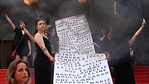 "Les Colleuses" hold a banner with names of 129 women who died in the last 12 months