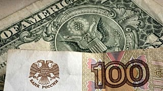 تم تصوير ورقة نقدية من فئة مائة روبل أمام ورقة ورقية بالدولار الأمريكي، غيلسنكيرشن، ألمانيا، الاثنين 25 أبريل 2022