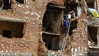 Lerombolt lakóházukból menekítenek ki tárgyakat emberek a Kijev melletti Irpinyben