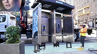 Workers remove the final New York City payphone in Midtown Manhattan