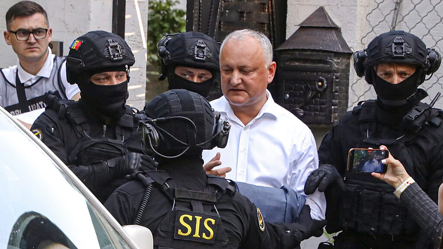 Members of Moldova's Information and Security service (SIS) escort former Moldovan President Igor Dodon to a van after he was detained at his house in Chisinau