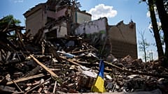 Ukrán zászló egy lebombázott épület mellett 2022. május
