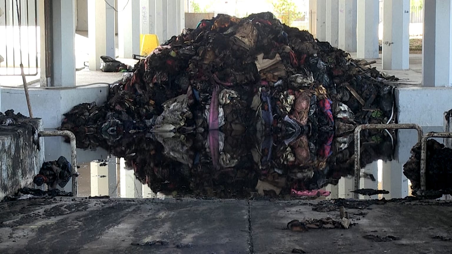A pile of destroyed bed linen and blankets, sits in a pool of water following a fire at the Peace and Friendship Stadium, in the Piraeus district of Athens, on May, 26, 2022.