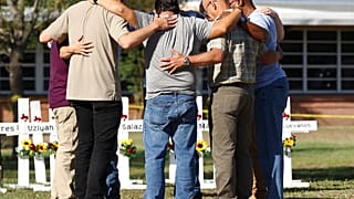 Un grupo de hombres forma un círculo para rezar por las víctimas frente al memorial de Uvalde