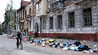 Frau auf dem Fahrrad im jetzt von russischen Truppen besetzten Mariupol
