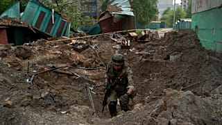 A special task force policeman inspects a site after an airstrike by Russian forces in Lysychansk on 13 May 2022