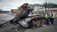 Road workers examine a destroyed Russian tank on the highway to Kyiv on 11 April 2022