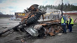 Road workers examine a destroyed Russian tank on the highway to Kyiv on 11 April 2022