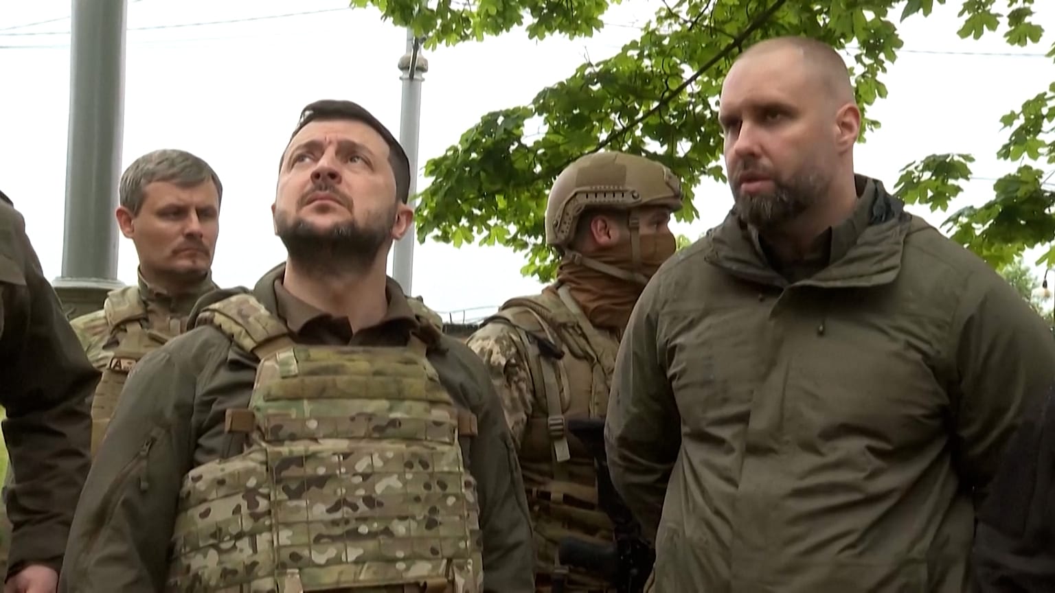 Volodymyr Zelensky walks near damaged buildings.