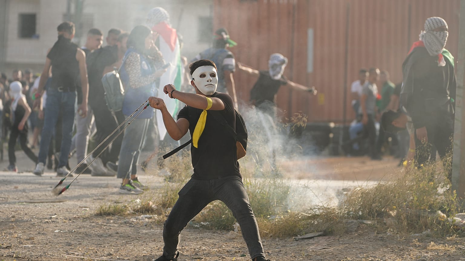 متظاهر فلسطيني يرشق القوات الإسرائيلية بالحجارة بالقرب من مدينة رام الله بالضفة الغربية بالتزامن مع "مسيرة الأعلام" الإسرائيلية في القدس 29 مايو 2022