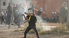 متظاهر فلسطيني يرشق القوات الإسرائيلية بالحجارة بالقرب من مدينة رام الله بالضفة الغربية بالتزامن مع "مسيرة الأعلام" الإسرائيلية في القدس 29 مايو 2022