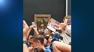 Un empleado del museo del Louvre limpia los restos de una tarta lanzada contra la Gioconda