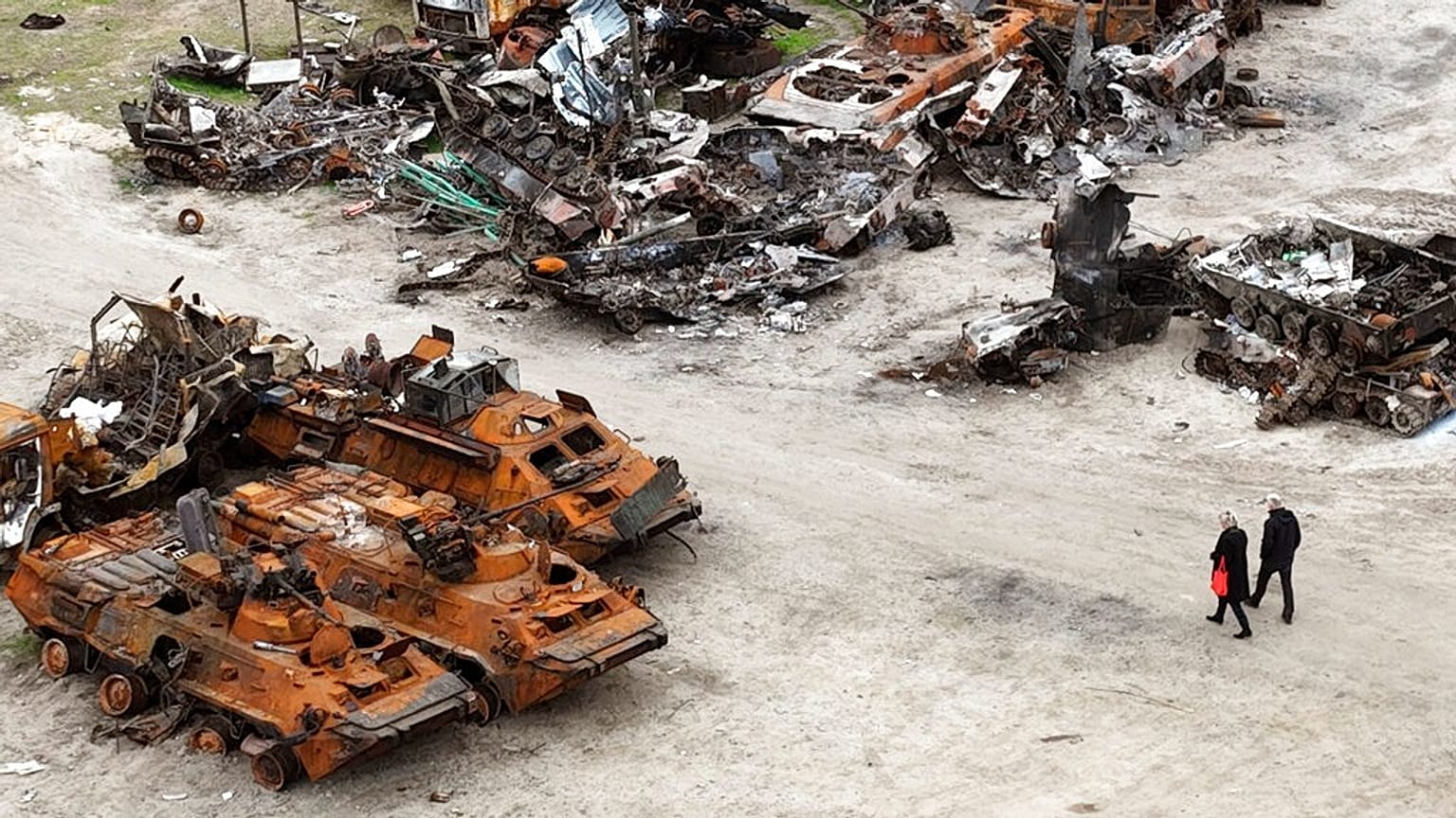 People walk past wrecks of military vehicles in Bucha, on the outskirts of Kyiv, Ukraine, April 30, 2022. 