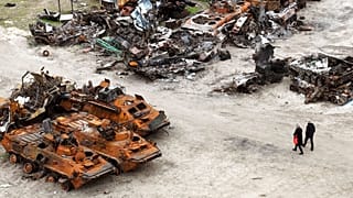 People walk past wrecks of military vehicles in Bucha, on the outskirts of Kyiv, Ukraine, April 30, 2022.