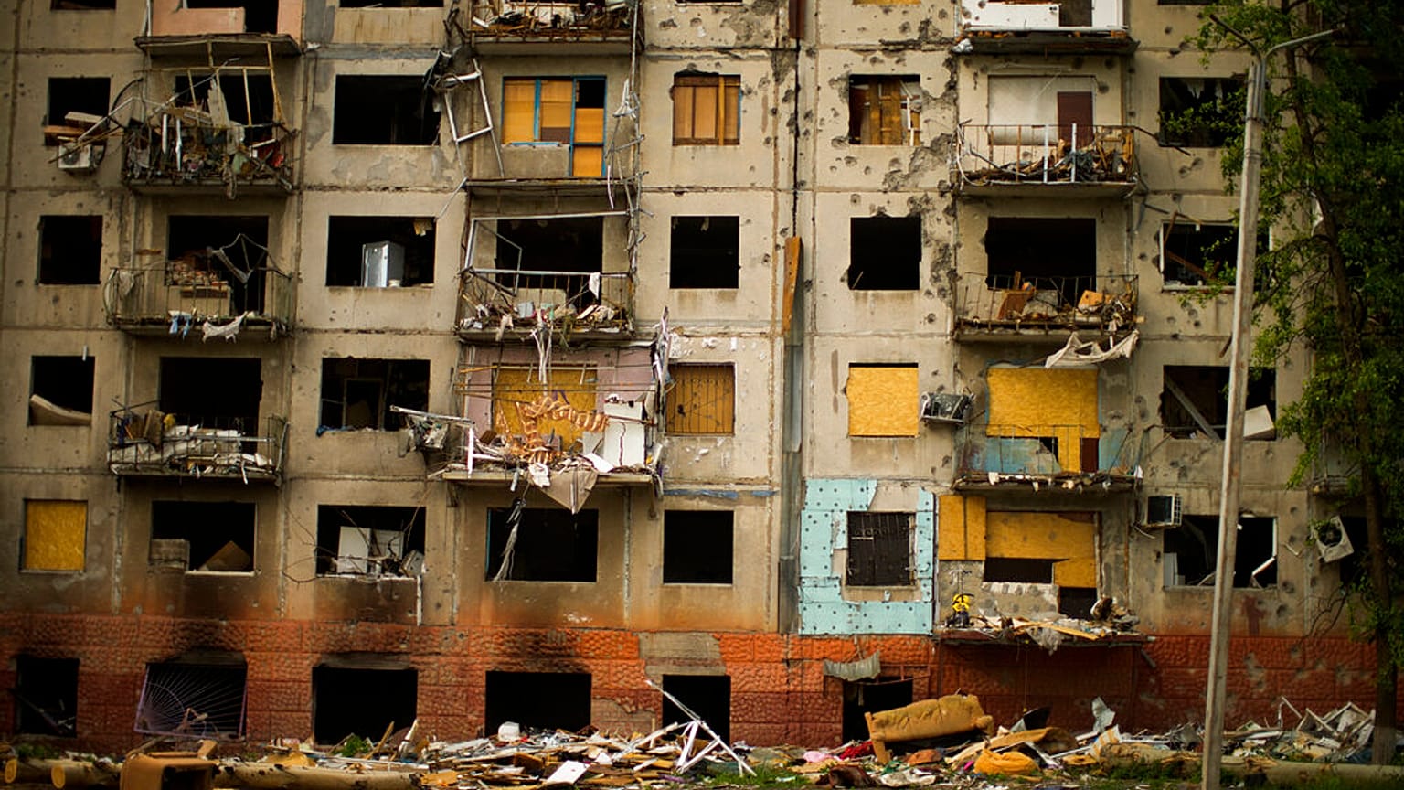 Debris hangs from a residential building heavily damaged in a Russian bombing earlier in the war in Kramatorsk, eastern Ukraine, Saturday, May 21, 2022